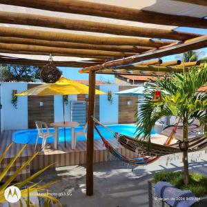 - un hamac et un parasol sur une terrasse avec une piscine dans l'établissement Casa na Ilha da Crôa/Barra de Santo Antônio, à Barra de Santo Antônio