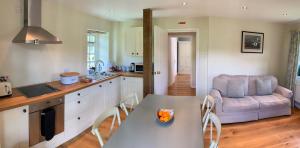 a kitchen and living room with a table and a couch at Luxury barn with tennis court in South Downs National Park in Chichester