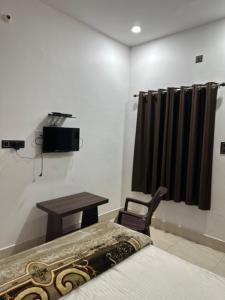 a bedroom with a bed and a table and a chair at Hotel Sharda Palace in Deoghar