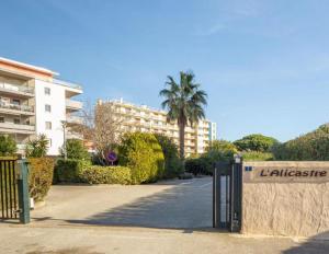 un panneau devant un bâtiment avec un palmier dans l'établissement L’azur, au Lavandou