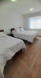 a bedroom with two beds and a wooden floor at Hostal Tabancura in Copiapó