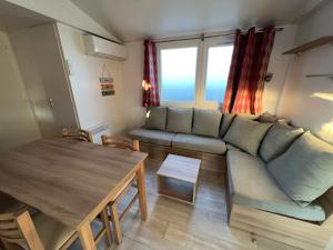 a living room with a couch and a table at mobilhome 6/8 pers. camping siblu les charmettes in Les Mathes