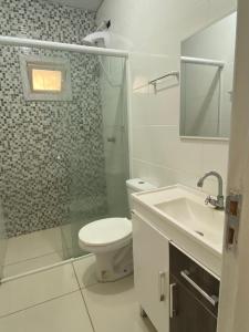 een witte badkamer met een toilet en een wastafel bij Casa Praia Perola in Passo de Torres