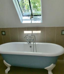 a bath tub in a bathroom with a window at Luxury barn with tennis court in South Downs National Park in Chichester