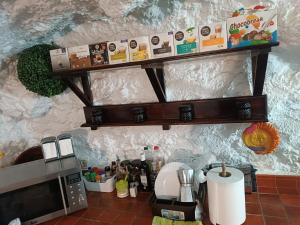 uma cozinha com um balcão com um micro-ondas e uma prateleira em Casa Cueva "El Mirador de Piedra" em Pegalajar