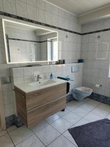 ein Badezimmer mit Waschbecken, Toilette und Spiegel in der Unterkunft Ahrtal Vier Sterne Ferienwohnungen Alexandra Weiler Panorama in Bad Neuenahr-Ahrweiler