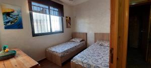 Zimmer mit 2 Betten, einem Tisch und einem Fenster in der Unterkunft StOony in Agadir