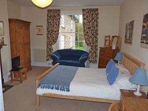 a bedroom with a bed and a chair and a window at Town Mills in Dulverton