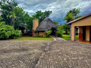 a house with a thatch roof and a brick driveway at Five Stars Lodge in Phalaborwa