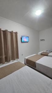 a hotel room with two beds and a flat screen tv at Pousada Casa Bella in Itaberaba