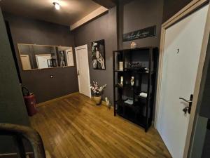 a living room with a wooden floor and a black book shelf at Atelier des Rêves in Aulnoye-Aymeries