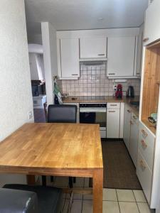Bürchenにある3-Zimmer Maisonette-Wohnungのキッチン(木製テーブル、白いキャビネット付)