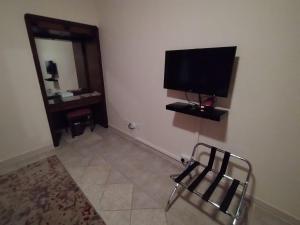 Habitación con silla y TV en la pared en فندق روتانة الحمراء en Yeda