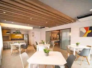 a dining room with tables and chairs and a kitchen at Duplex Luxo Vista Parque Bariguí in Curitiba