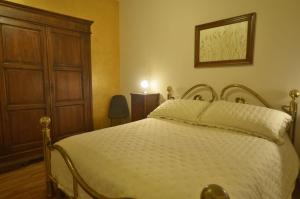 1 dormitorio con 1 cama blanca y armario de madera en Appartamento Val d'Orcia Patri en Piancastagnaio