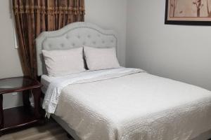 uma cama com lençóis brancos e almofadas num quarto em Cozy Luxurious Detached 4 Bedroom House em Guelph