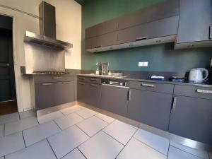 cocina con armarios grises y suelo de baldosa blanca en Magnifique maison avec terrasse en Château-Thierry