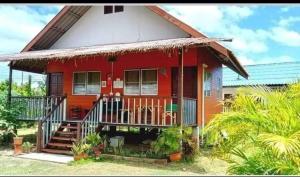 una casa roja con una escalera delante de ella en บ้านสวนยายชุ่ม/bannsuanyaychum, en Lampang