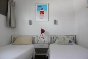 Duas camas num quarto com paredes brancas em Relaxing Bungalow Playa del Inglés em Maspalomas