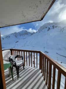 un banco sentado en una terraza con montañas cubiertas de nieve en Appartements pied des pistes - Résidence Mongie - Tourmalet en La Mongie