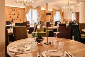 a restaurant with tables and chairs and a large clock at Hotel Salvadori in Mezzana