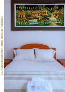 a bedroom with a bed with a picture on the wall at Hospedaje Moralillos in Yurimaguas