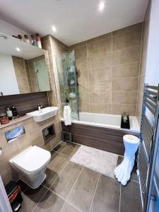 uma casa de banho com uma banheira, um WC e um lavatório. em Modern 14th Floor 1or2-Bed Flat em Dagenham