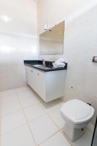 uma casa de banho branca com um WC e um espelho. em Suíte 1 - Pousada Karaiba em Uberlândia