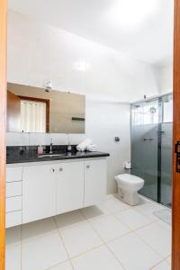 uma casa de banho branca com um lavatório e um WC em Suíte 1 - Pousada Karaiba em Uberlândia