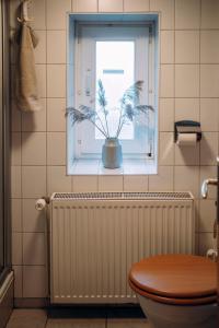 a bathroom with a toilet and a window with a plant at Kalle´s Reethus in Pellworm