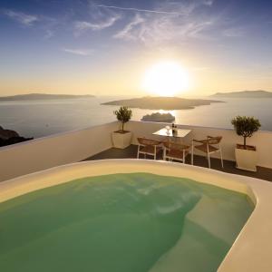 a pool on the roof of a house with the sunset at Kamares Apartments in Fira