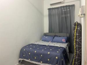 a small bedroom with a bed with a blue comforter at Nilai Bronizam Homestay in Nilai