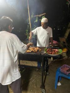 un hombre y una mujer preparando comida en una parrilla en Nilai Bronizam Homestay, en Nilai