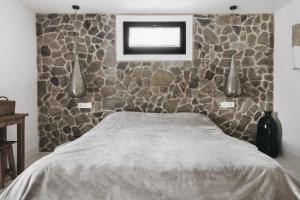 um quarto com uma parede de pedra e uma cama em Cortijo Almarchal em El Almarchal
