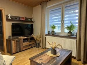 a living room with a television and a coffee table at Christels Ferienwohnung 2 in Thale mit überdachter Terrasse, Küche mit TV & Geschirrspüler in Thale