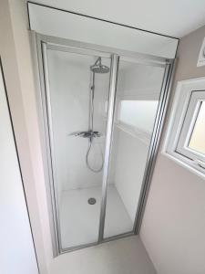 a glass shower in a room with a window at Nieuw Noorderland op Terschelling in Midsland
