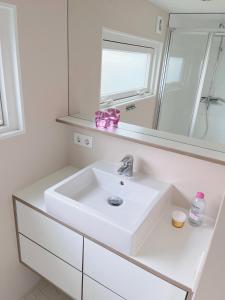 a white bathroom with a sink and a mirror at Nieuw Noorderland op Terschelling in Midsland