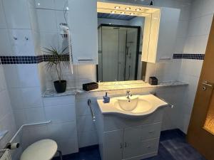 a white bathroom with a sink and a mirror at Christels Ferienwohnung 2 in Thale mit überdachter Terrasse, Küche mit TV & Geschirrspüler in Thale +22 photos