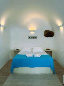 a bedroom with a bed with two towels on it at Lioyerma Cave Villa With Private Outdoor Hot Tub in Oia