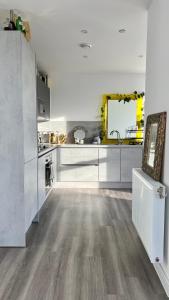 uma cozinha com armários brancos e piso em madeira em Modern 14th Floor 1or2-Bed Flat em Dagenham