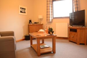 sala de estar con mesa y TV en Lochview House, en Fort William