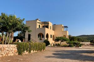 a large white house with trees and a stone wall at Giannikas Apartments in Livadi