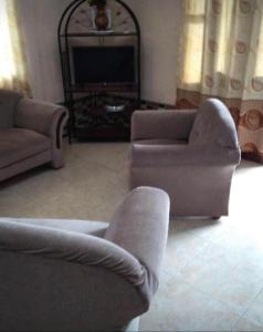 a living room with two couches and a television at Kapowlito Real Estate Casa Sitalweg in Paramaribo