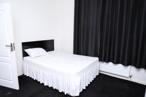 a bedroom with a white bed with a black curtain at Beautiful and spacious 4- bedroom house in Sunderland in Pallion