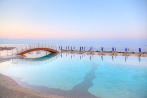 a bridge over a pool of water with chairs and umbrellas at 19 Summer Suites in Santa Cesarea Terme