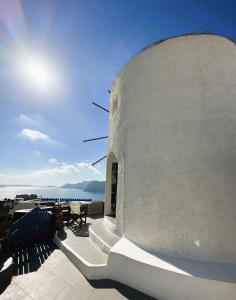 a white building with a view of the ocean at Lioyerma Windmill Villa With Outdoor Hot Tub in Oia