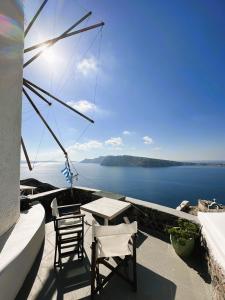a table and chairs on a balcony with a view of the water at Lioyerma Windmill Villa With Outdoor Hot Tub in Oia