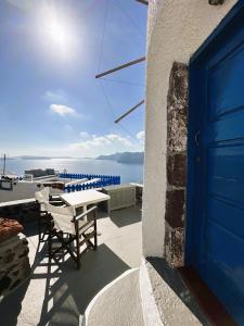une porte bleue sur une maison avec une table et des chaises dans l'établissement Lioyerma Windmill Villa With Outdoor Hot Tub, à Oia