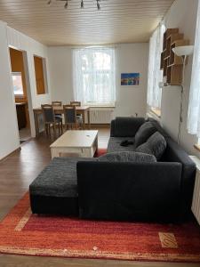 a living room with a black couch and a table at Ferienwohnung in Walddorf
