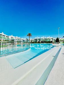 una piscina nel resort con una palma e degli edifici di Casa Dunaflor a Maspalomas